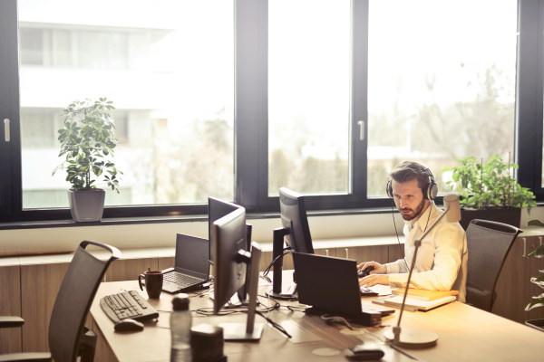 Man with headphones facing computer monitor