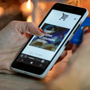 Person using black and white smartphone and holding blue card