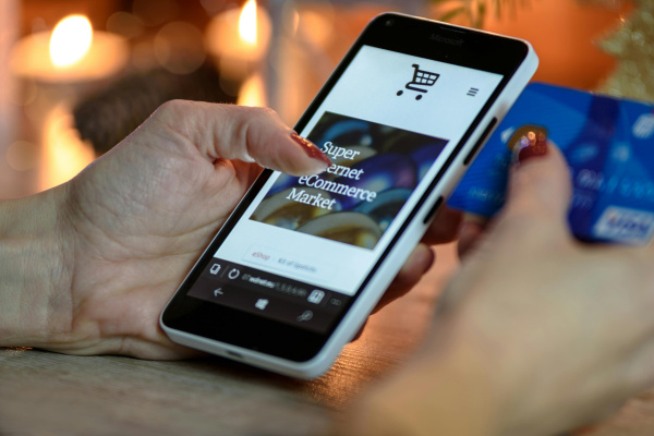 Person using black and white smartphone and holding blue card